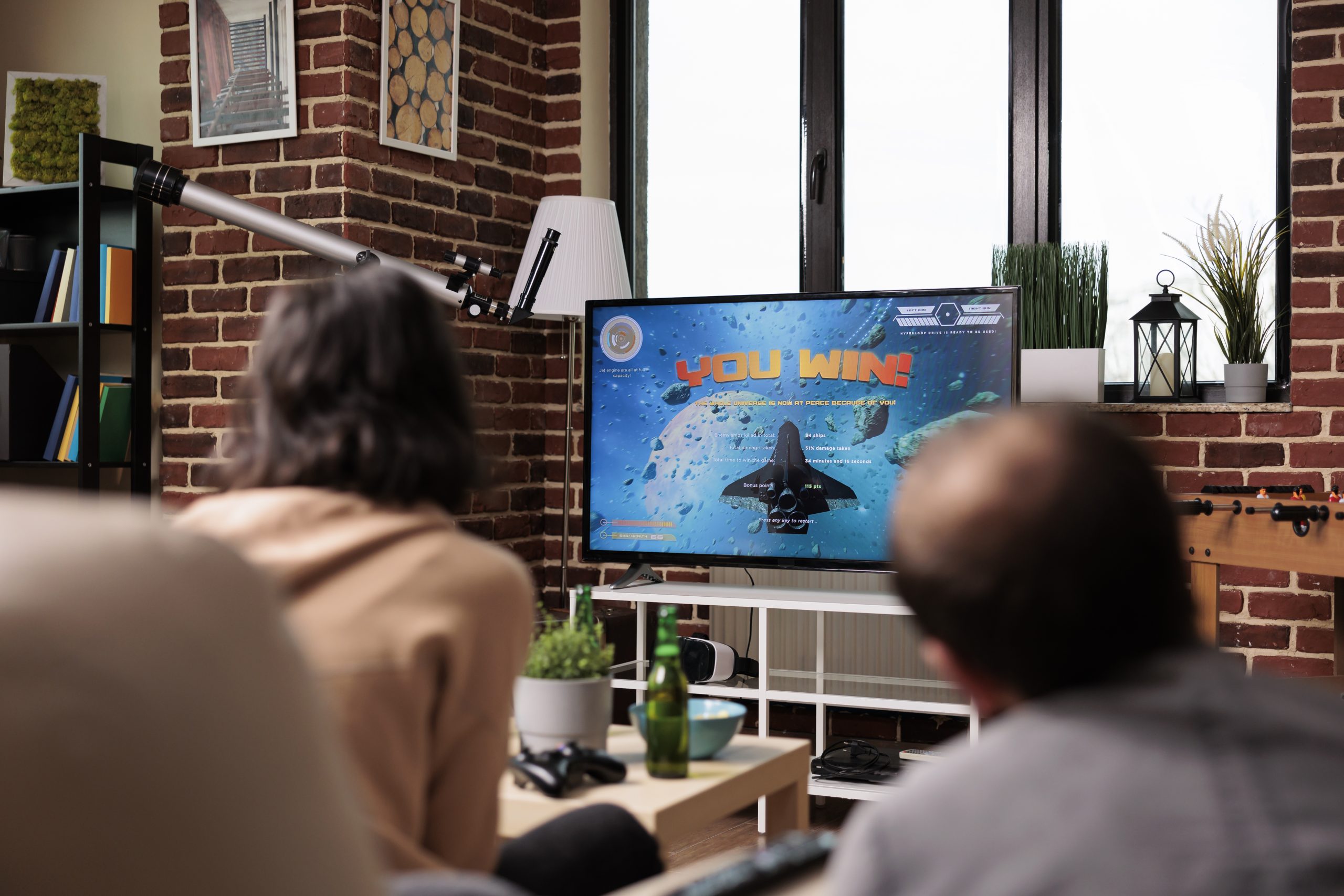 Playful multiethnic group of friends sitting on sofa while playing console videogames with controller.